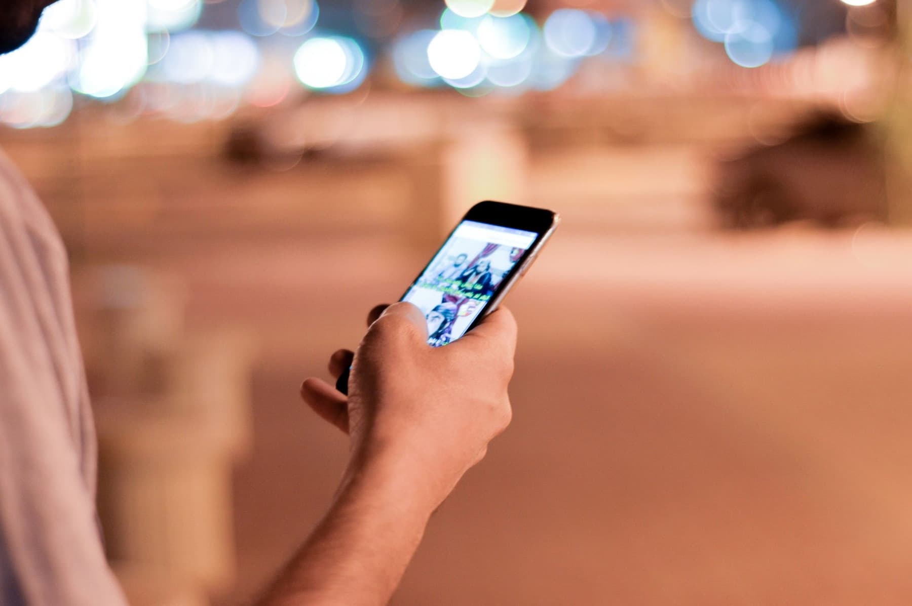 Someone using their phone on a city street at night