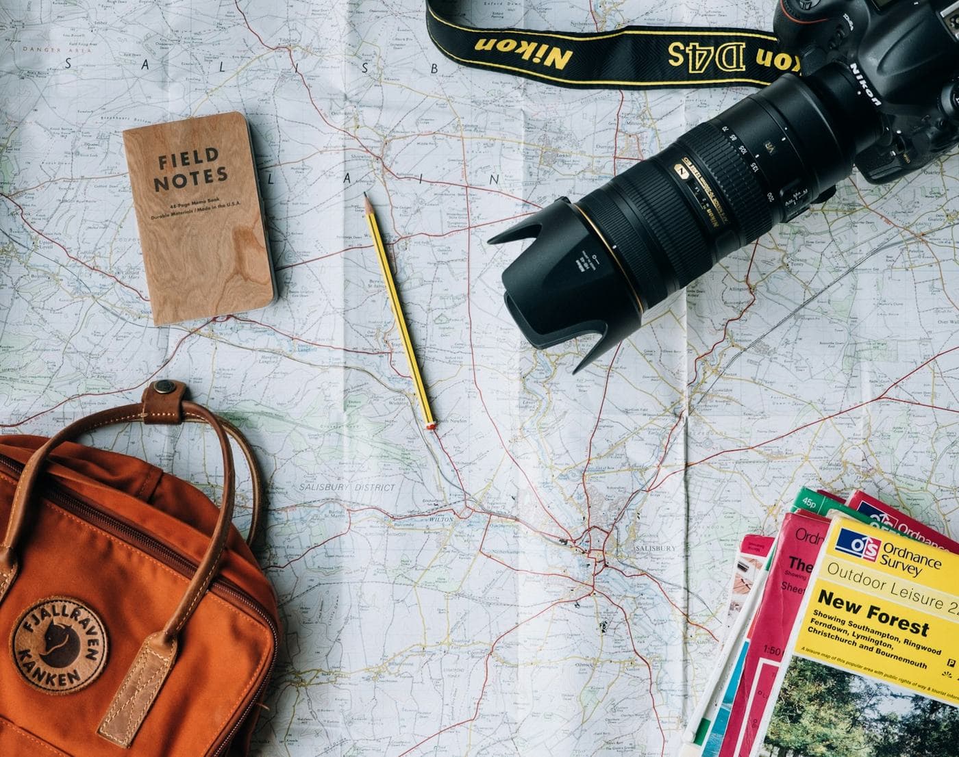 A travel map, a notebook and a backpack laid out for a trip, for study and travel in one place